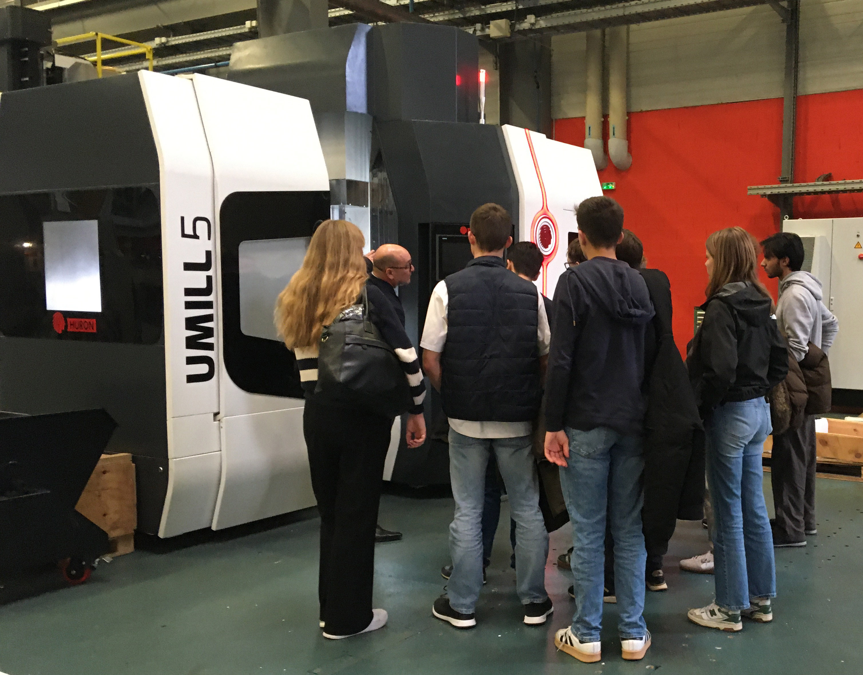 Étudiants observant un centre d’usinage haute précision Huron dans l’atelier.